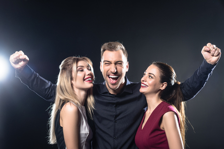 happy celebrating man and women looking at camera on blackの写真素材