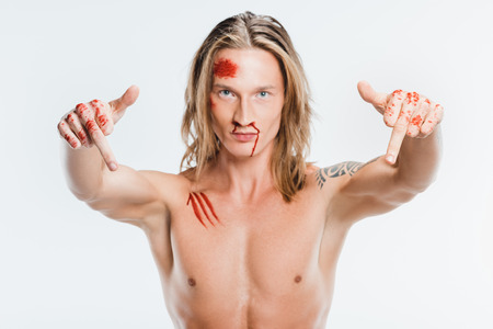nude handsome man with bloody wounds showing middle fingers isolated on whiteの写真素材