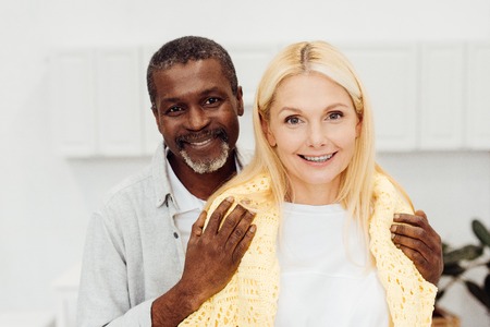 happy african american man embracing smiling blonde womanの写真素材