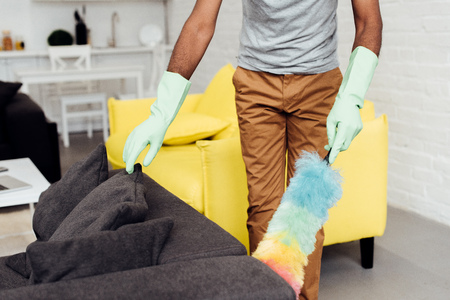 cropped view of male african american hands in rubber gloves with dusterの写真素材