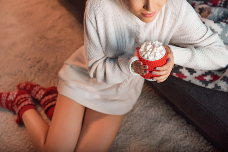 beautiful woman in christmas patterned socks drinking cocoa