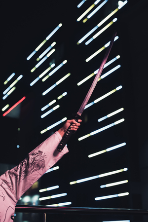 cropped image of girl in white kimono holding katana on street with neon light in evening, city of future conceptの写真素材