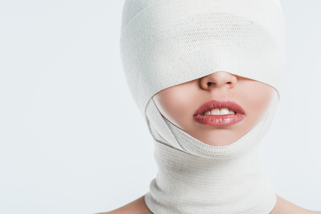 close up of woman face with white bandages isolated on whiteの写真素材
