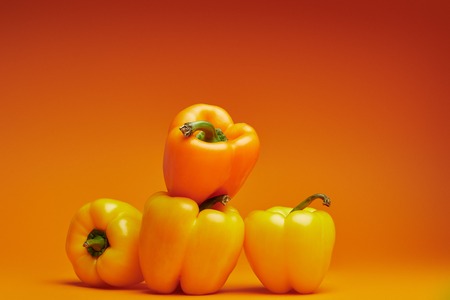close-up view of fresh organic bell peppers on orangeの写真素材