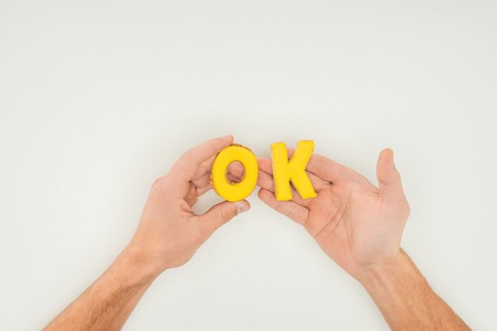 cropped person holding ok word in yellow cookies solated on white backgroundの写真素材