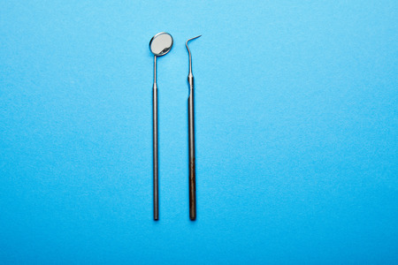 top view of dental mouth mirror and probe on blue surface, dental care conceptの写真素材