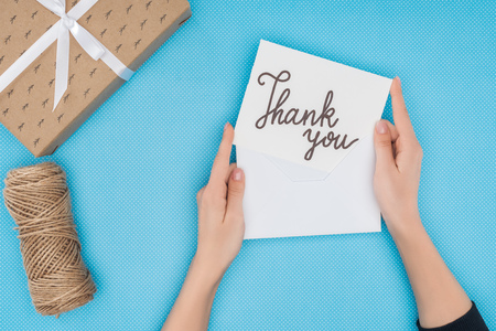 cropped person holding paper with thank you lettering isolated on blue backgroundの写真素材