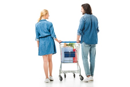 Back view of couple holding shopping cart with bags isolated on whiteの写真素材