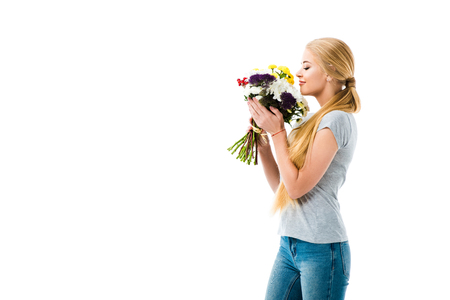 Beautiful girl smelling bouquet of flowers isolated on whiteの写真素材