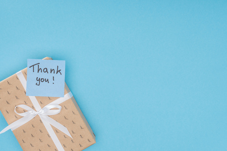 sticky note with thank you lettering on gift box isolated on blue backgroundの写真素材