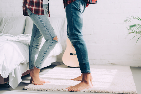 partial view of couple in jeans standing next to each other in bedroom at homeの写真素材