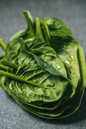 Wet organic spinach leaves with water drops on grey backgroundの写真素材
