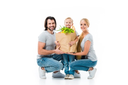 Happy smiling family with grocery bag full of healthy food isolated on whiteの写真素材
