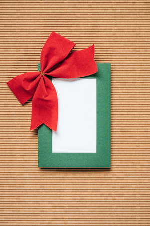 top view of green christmas frame with red bow on textured backgroundの写真素材