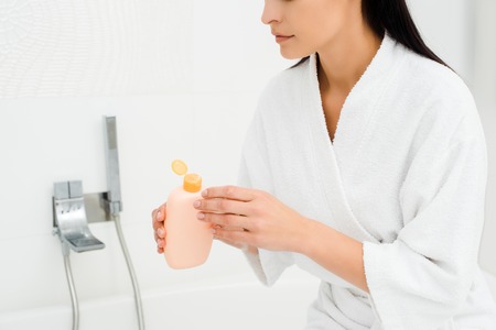 Woman holding bottle with lotion in white bathroomの写真素材