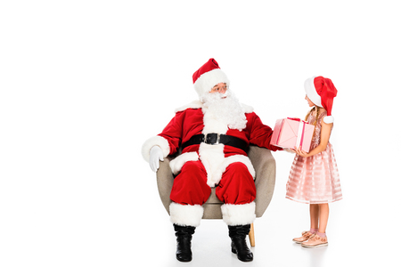 santa claus sitting in armchair and giving present to little child isolated on whiteの写真素材