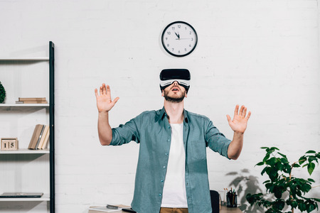selective focus of young man with wide arms using virtual reality headset at home
