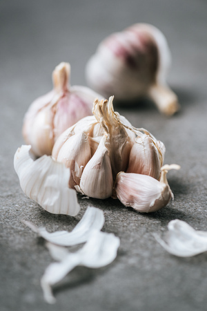 Close up view of ripe garlic bulbs and husk on grey surfaceの写真素材