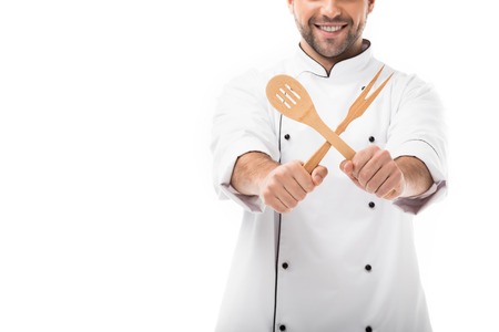 cropped shot of smiling young chef holding wooden kitchen utensils isolated on whiteの写真素材