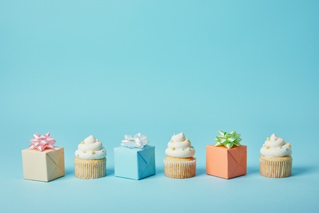 Delicious cupcakes and diffrent gifts on blue backgroundの写真素材