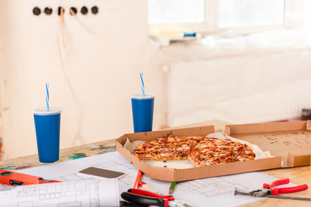 selective focus of pizza, soda, blueprint, tools and smartphone with blank screen on tableの写真素材
