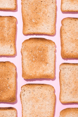 top view of pattern of crispy toasts on pink surfaceの写真素材