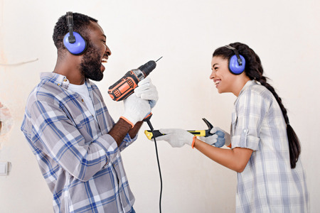 couple playing with drill and hammer while making renovation of home
