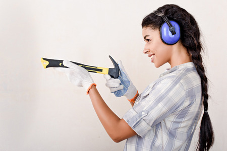 playful young woman having fun with hammer during renovation of homeの写真素材