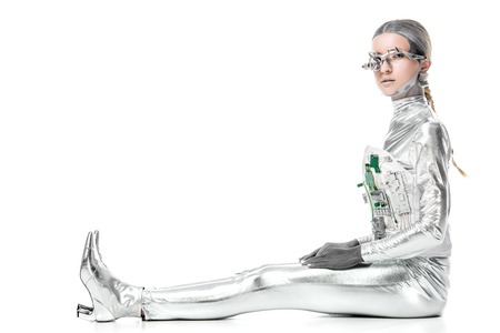 side view of silver robot sitting and looking at camera isolated on white, future technology conceptの写真素材