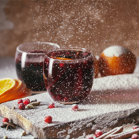 homemade mulled wine with cranberries and falling powdered sugar in kitchenの写真素材