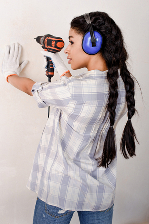 beautiful young woman drilling wall during renovation of homeの写真素材