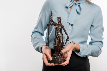 close-up partial view of female lawyer holding lady justice statue isolated on whiteの写真素材