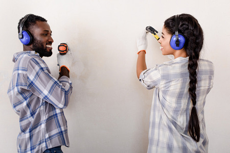 couple making renovation of home with drill and hammer togetherの写真素材