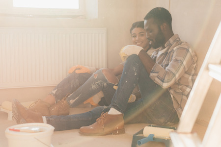 beautiful young couple relaxing on floor while making renovation of homeの写真素材