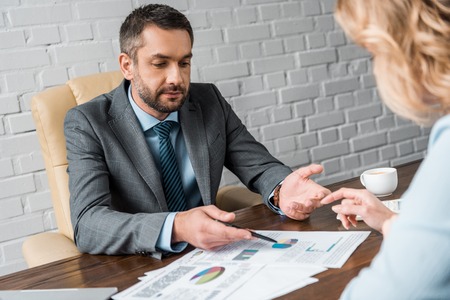 cropped shot of businessman and female colleague working with charts and graphs in officeの写真素材