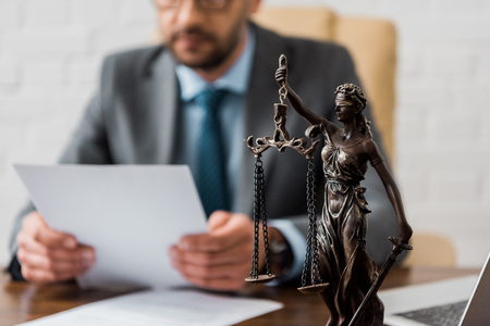 close-up view of lady justice statue and lawyer working working with papers behindの写真素材