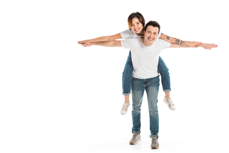 smiling husband giving wife piggyback ride isolated on white, couple having funの写真素材