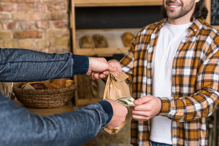 cropped view of customer giving money to seller and taking paper bagの写真素材