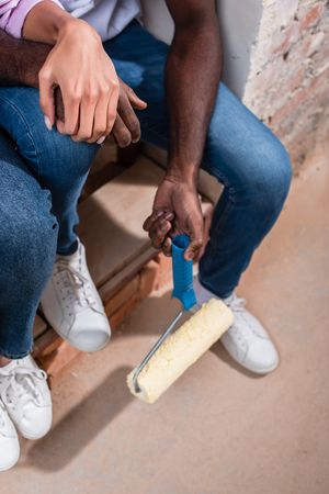 cropped shot of couple with roller brush sitting on stairs making renovation of homeの写真素材