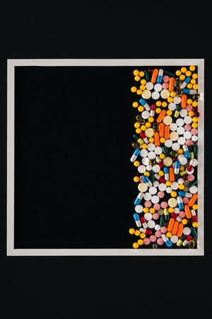 view from above of frame with pile colorful various pills isolated on blackの写真素材