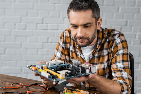 serious handsome computer engineer holding motherboardの写真素材