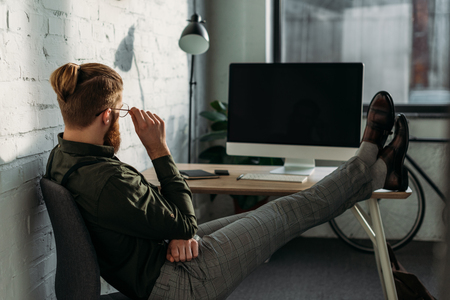 side view of businessman sitting with legs on office tableの写真素材