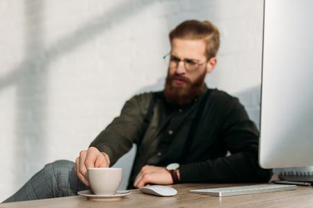businessman taking cup of coffee from working tableの写真素材