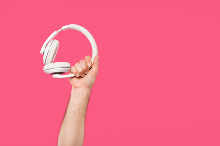 cropped shot of man holding white headphones isolated on pinkの写真素材