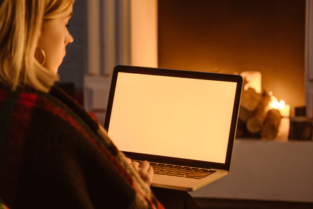 cropped view of young woman using laptop with blank screen at home