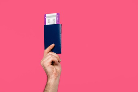 cropped shot of man holding passport and boarding pass isolated on pinkの写真素材