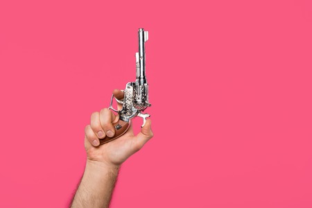 cropped shot of man holding revolver isolated on pink