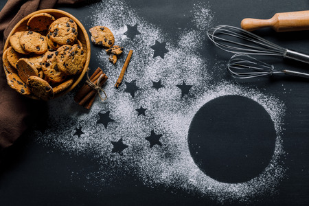 view from above of cookies in bowl, whisks and rolling pin on table covered by flour with symbol of starsの写真素材