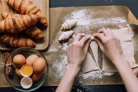 cropped image of woman rolling dough for croissants on baking paper covered by flour near ingredientsの写真素材
