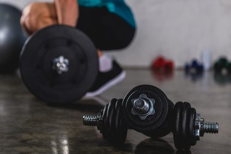 sportsman training with barbell, dumbbells lying on floor on foregroundの写真素材